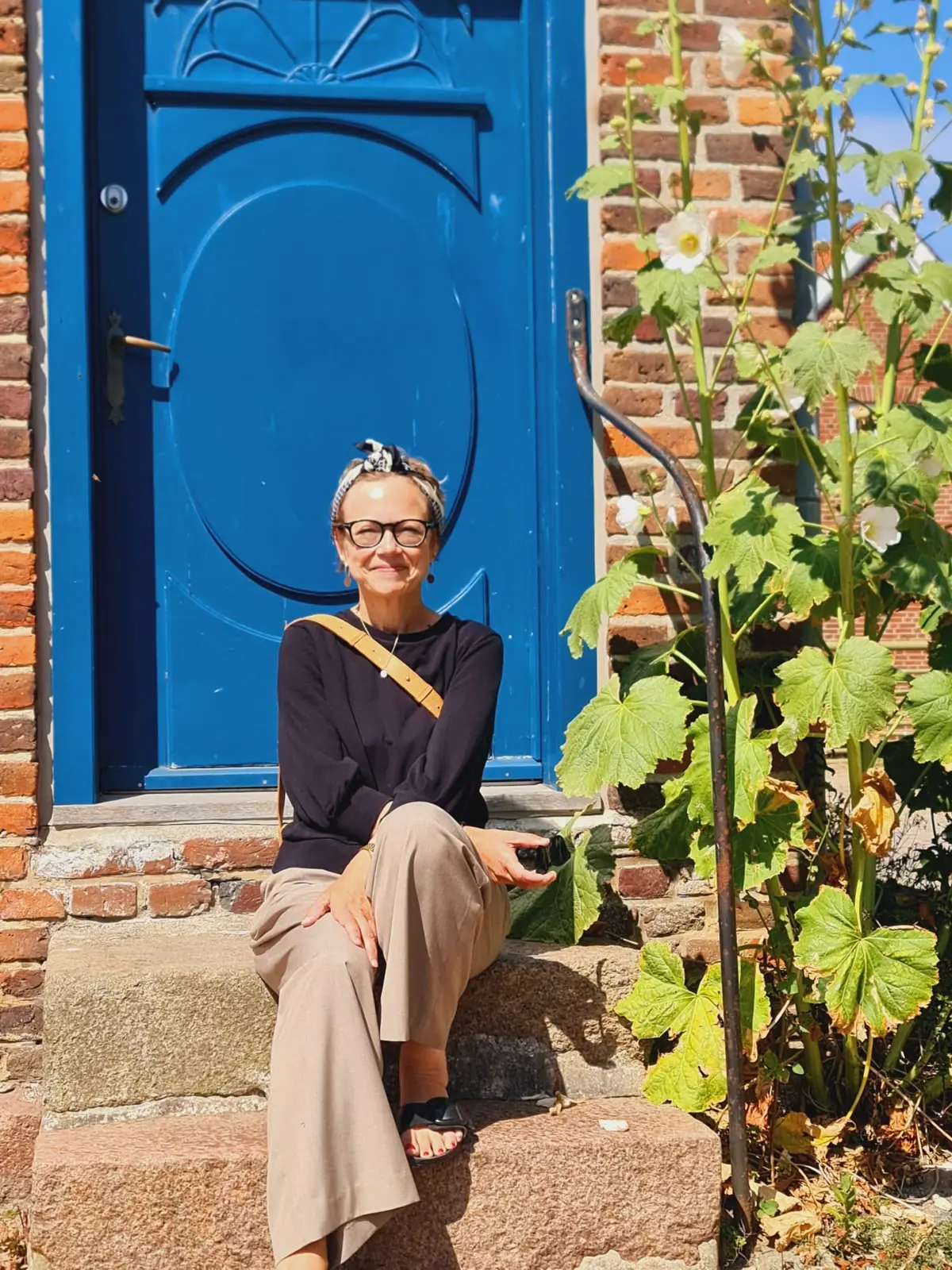 Hochzeitsrednerin Yvonne Mende sitzt auf einer Treppe vor einer blauen Tür