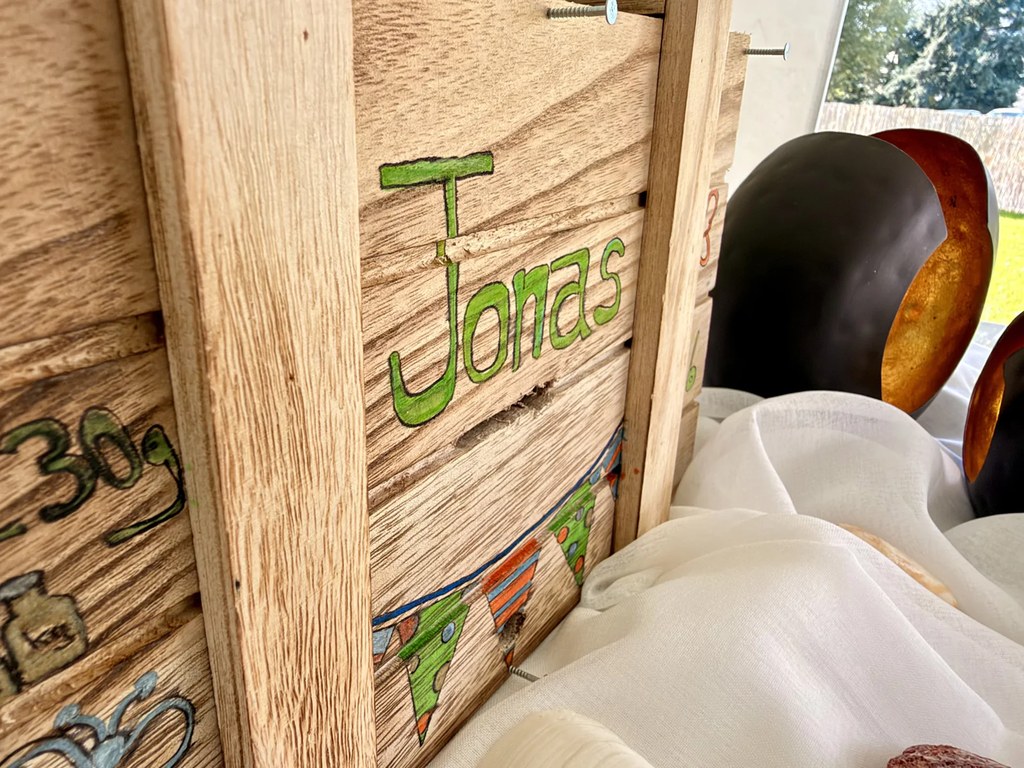 Holzkiste mit Jonas' Namen für Erinnerungen an die Willkommensfeier